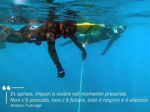 Due apneisti nuotano sott'acqua, uno vicino alla superficie. Imparare a trattenere il respiro, come rompere il fiato, porta a vivere il momento presente.