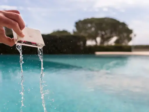 Mano che versa acqua da un contenitore per testare il cloro della piscina.
