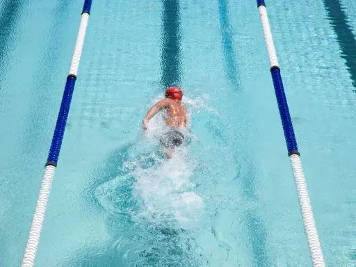 Nuotatore in corsia, godendosi i benefici del nuoto libero. L'acqua cristallina e il movimento fluido del corpo evidenziano la libertà e il benessere.