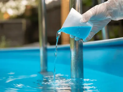 Versando antialghe piscina. Dopo quanto fare il bagno? La soluzione azzurra cade in acqua limpida.