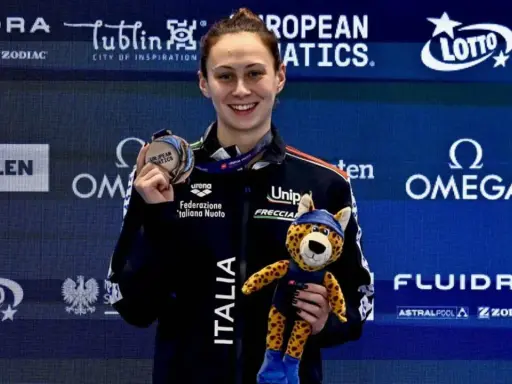 Anita Gastaldi sorride con una medaglia al collo e un peluche di ghepardo, celebrando una vittoria.