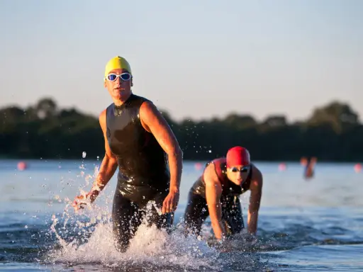 Atleti in muta escono dall'acqua, pronti per la corsa dopo il nuoto.