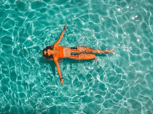 Donna rilassata galleggia in piscina. Il nuoto è un ottimo modo per migliorare la forma fisica, con risultati visibili nel nuoto cellulite prima e dopo.