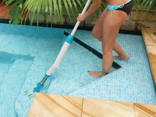 Donna usa un aspiratore per pulire il fondo della piscina, rimuovendo foglie e detriti per un'acqua cristallina.