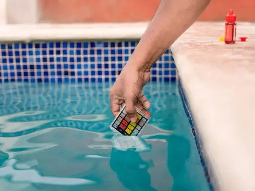 Mano immerge kit test pH nell'acqua della piscina, per assicurarsi che non sia acqua viscida.