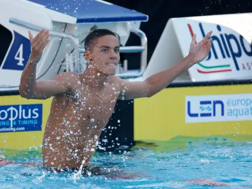 David Popovici esulta in piscina, circondato da schizzi d'acqua, con il numero 4 sulla corsia.