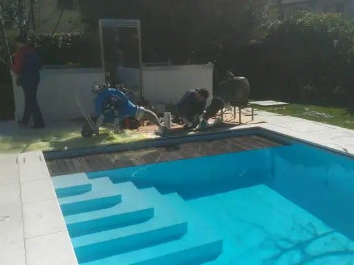 Tecnici al lavoro su una piscina Bestway che perde acqua da sotto, con attrezzature per la riparazione.