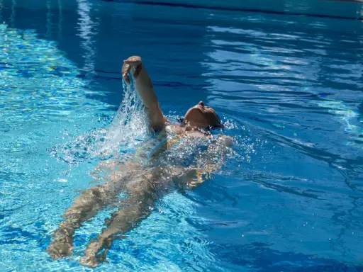 Donna nuota a dorso in una piscina olimpionica, godendosi la profondità e la frescura dell'acqua cristallina.