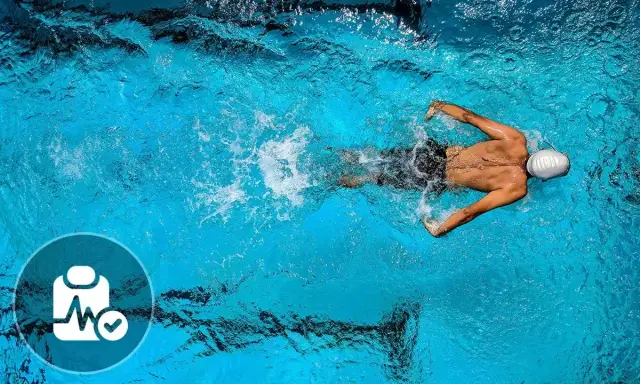 Nuotatore in piscina, con icona di controllo medico. Nonostante i benefici, ci sono anche svantaggi del nuoto da considerare.