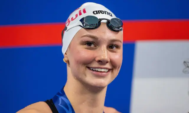 Sorriso raggiante di Summer McIntosh, nuotatrice con cuffia e occhialini, pronta per una gara.