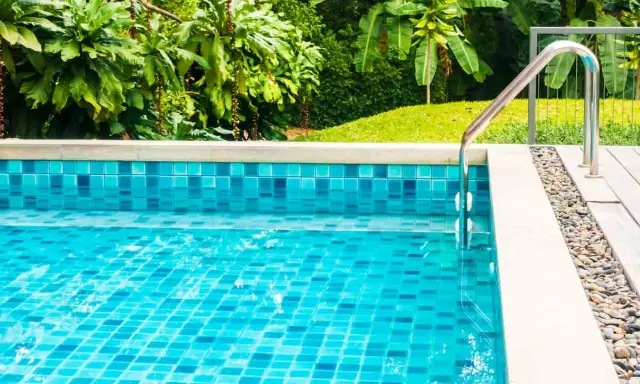 Piscina fuori terra con piastrelle blu scintillanti e vegetazione lussureggiante. La manutenzione piscina fuori terra è fondamentale per godersi questo angolo di paradiso.