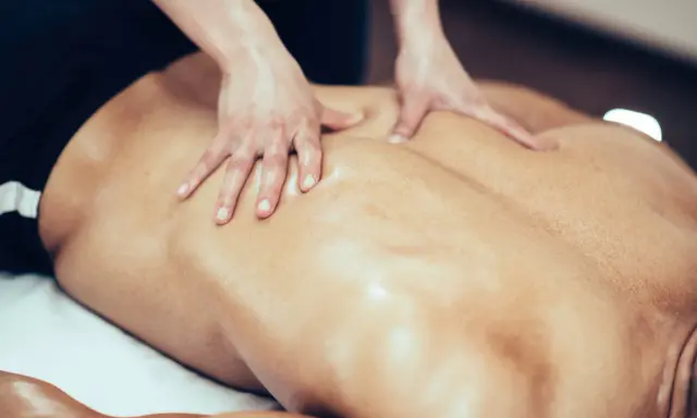 Mani esperte massaggiano la schiena di un nuotatore, sciogliendo la tensione muscolare dopo un allenamento intenso.