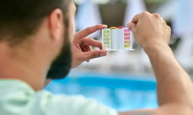 Uomo controlla il kit per acidificare l'acqua della piscina, analizzando i livelli di pH e cloro.