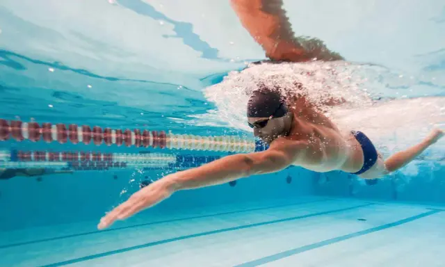 Un uomo nuota a stile libero in piscina, un ottimo modo per capire quanto nuotare per dimagrire e mantenersi in forma.