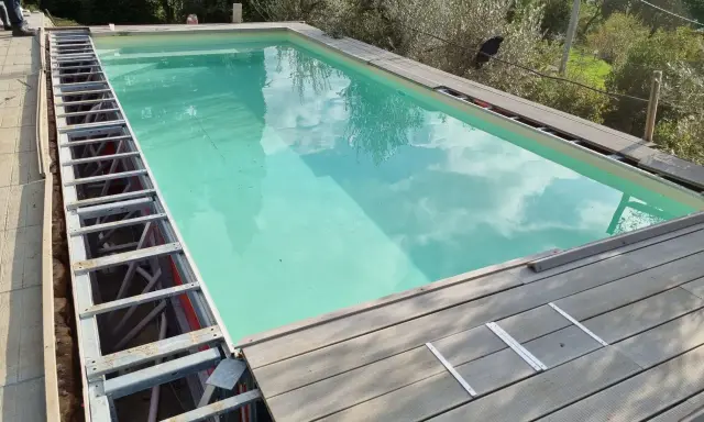 Struttura metallica a vista per piscina fuori terra, con pannelli in legno in fase di posa. Si nota un leggero cedimento della struttura.