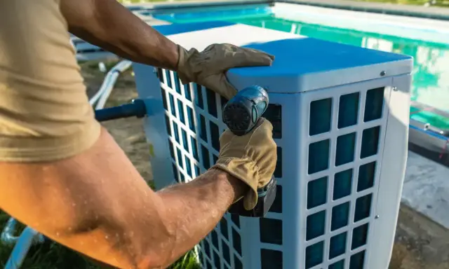 Installazione di un sistema per riscaldare acqua piscina fai da te. Un uomo con guanti avvita un componente.