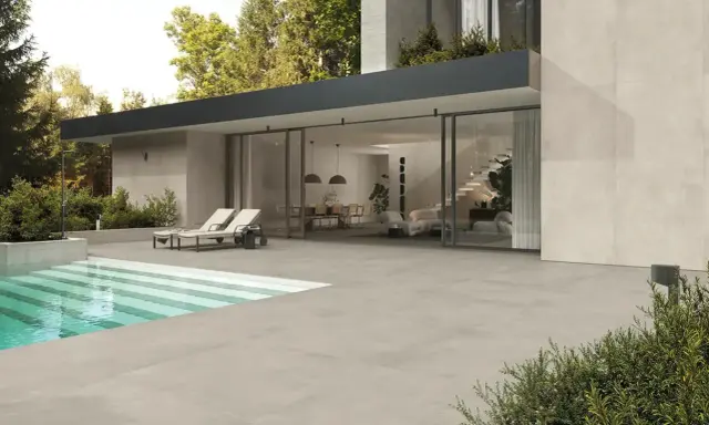 Moderna villa con piscina e ampia pavimentazione bordo piscina in gres. Due lettini prendisole invitano al relax.