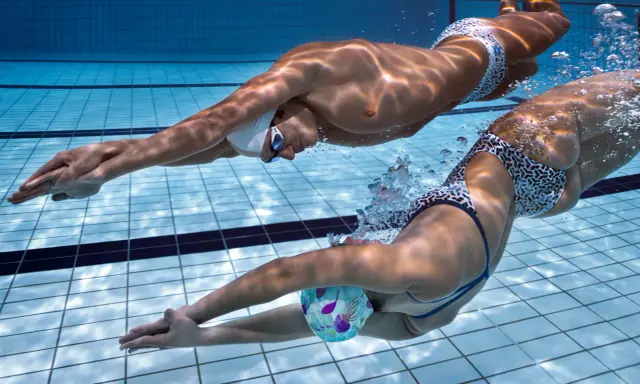 Due nuotatori si allenano in piscina, un uomo e una donna, in un intenso allenamento ipossico.