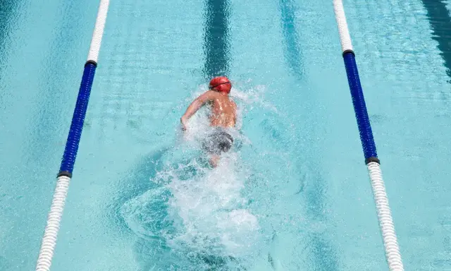 Nuotatore in corsia, godendosi i benefici del nuoto libero. L'acqua cristallina e il movimento fluido del corpo evidenziano la libertà e il benessere.