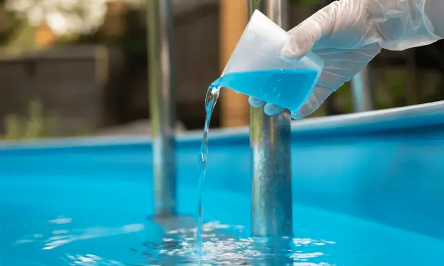 Versando antialghe piscina. Dopo quanto fare il bagno? La soluzione azzurra cade in acqua limpida.