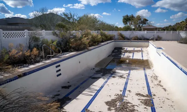 Piscina vuota e sporca, con detriti sul fondo. Immagina come svuotare la piscina con la pompa a sabbia per riportarla al suo antico splendore.