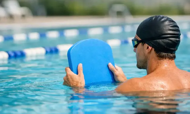 Uomo in piscina con tavoletta blu, pronto per il nuoto con tavoletta per dimagrire.