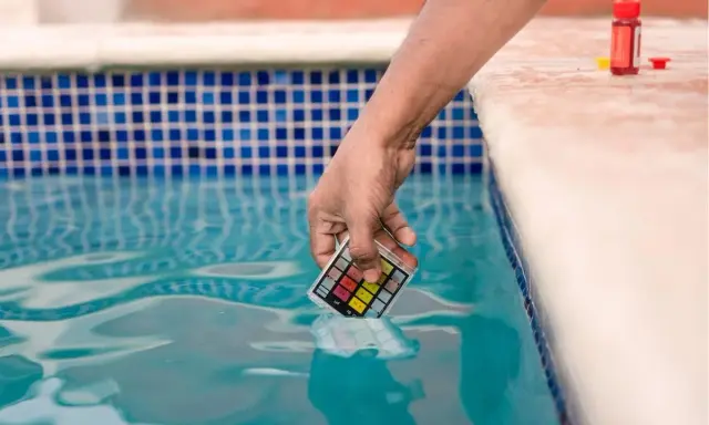 Mano immerge kit test pH nell'acqua della piscina, per assicurarsi che non sia acqua viscida.