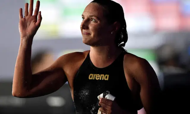 Katinka Hosszu, bagnata e sorridente, saluta con la mano dopo una gara.