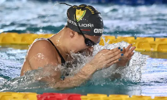 Arianna Castiglioni in azione, con schizzi d'acqua che la circondano durante una gara di nuoto.