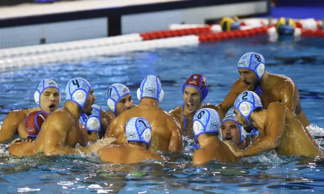 Giocatori di pallanuoto in acqua, con cuffie numerate, in un momento di intensa competizione. I loro ruoli pallanuoto sono evidenti dalla loro posizione e dall'azione.