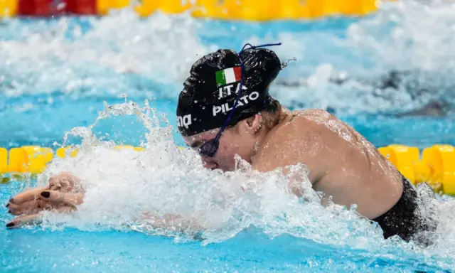 Chiara della Corte, nuotatrice italiana, in azione, con la bandiera tricolore sul costume.