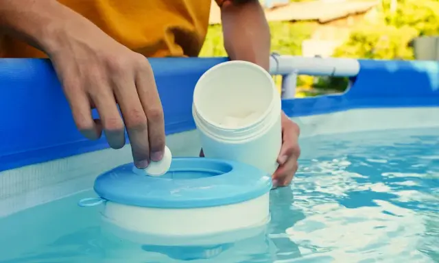 Mano inserisce una pastiglia nel galleggiante per la piscina. Un modo semplice per capire come pulire il filtro della piscina.