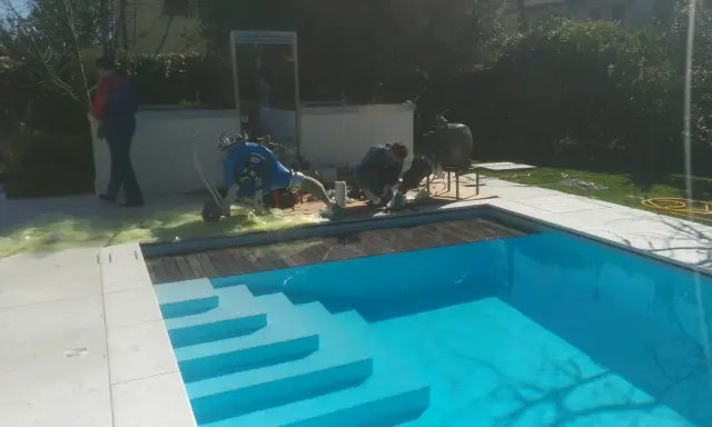 Tecnici al lavoro su una piscina Bestway che perde acqua da sotto, con attrezzature per la riparazione.