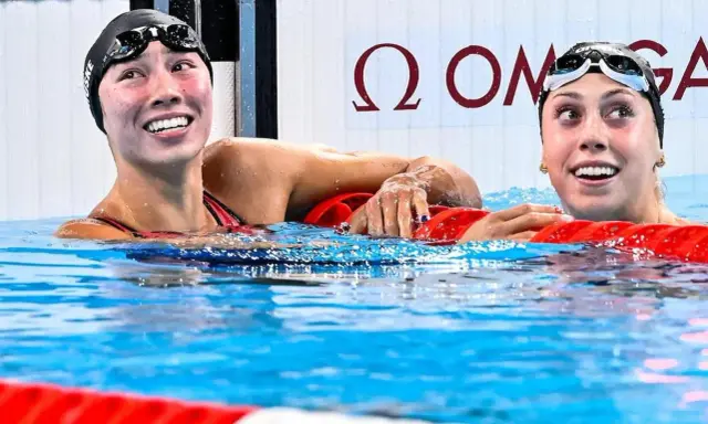 Due nuotatrici sorridono nell'acqua, una con il cappellino "Torri Huske".