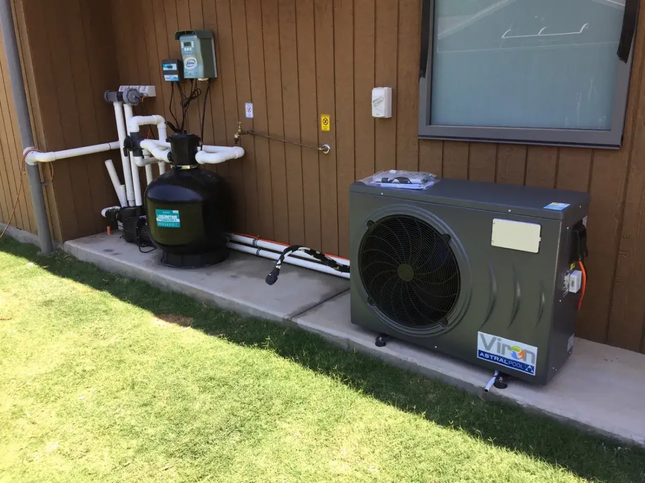 Sistema per riscaldare acqua piscina fai da te: pompa di calore, filtro e centralina installati all'esterno.