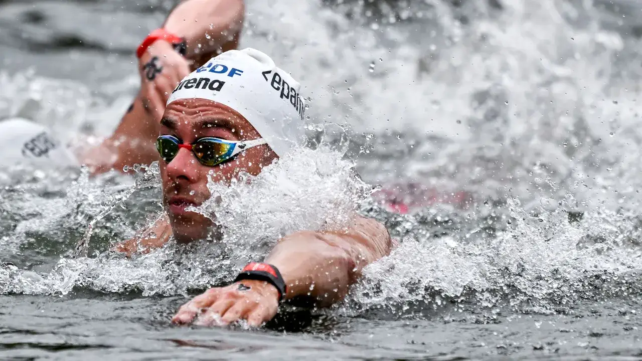 Nuotatore in azione, concentrato e determinato, durante una staffetta 4x100. L'acqua schizza intorno a lui, creando un'immagine dinamica e potente.