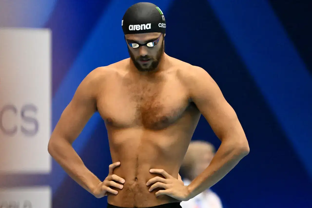 Nuotatore italiano con cuffia e occhialini, mani sui fianchi, pronto a gareggiare. Pan Zhanle, un nome che risuona nel nuoto.