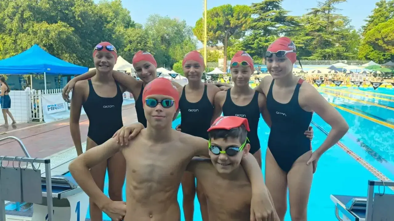 Giovani nuotatori sorridono in piscina, tra cui Rachele Ceracchi, pronti per la gara.