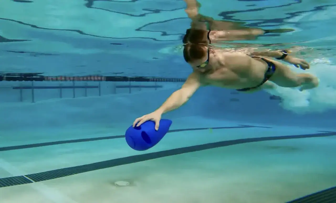 Uomo nuota in piscina con tavoletta blu per un allenamento efficace.