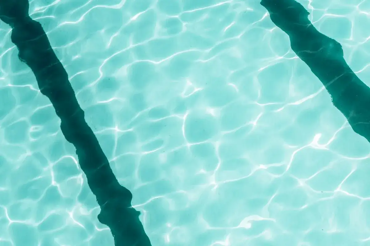 Acqua cristallina di piscina con riflessi solari. Dopo aver usato antialghe piscina, dopo quanto fare il bagno?