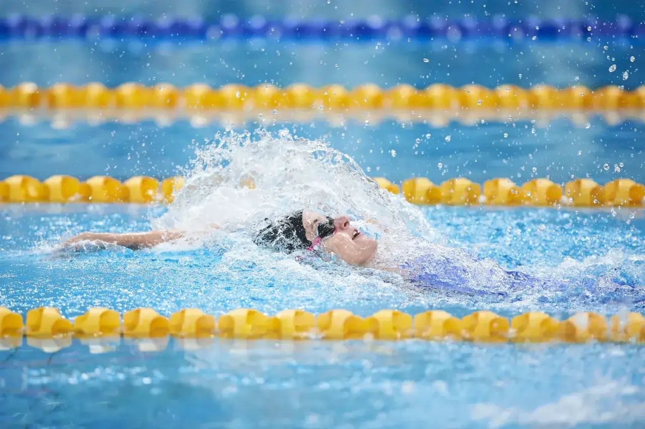 Axana Merckx nuota con determinazione, sollevando spruzzi d'acqua in piscina.