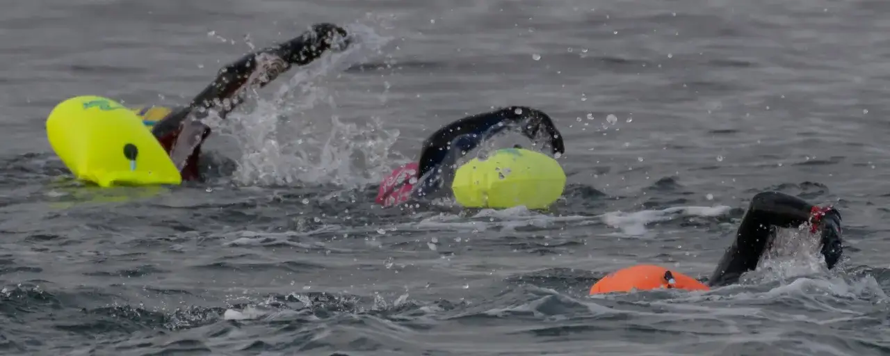Nuotatori in mare con boe colorate, godendosi i benefici nuoto libero per corpo e mente.