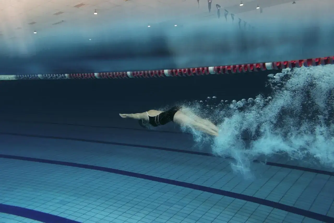Luca Oliva nuota sott'acqua in una piscina, creando una scia di bollicine.