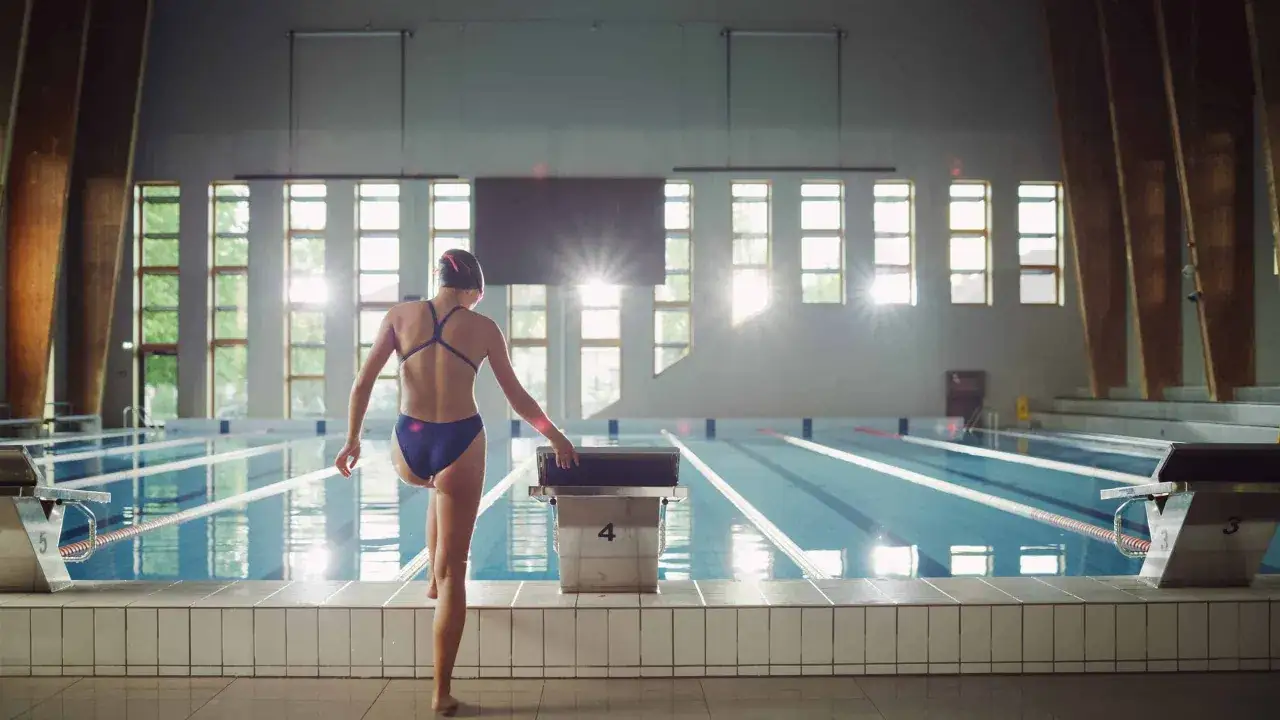 Nuotatrice si prepara a tuffarsi in piscina. Ogni vasca nuoto calorie bruciate &egrave; un passo verso il benessere.