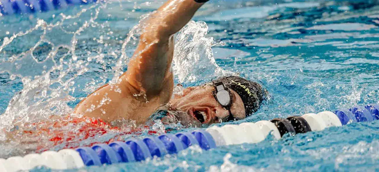 Nuotatore in azione, con schizzi d'acqua, che mostra come allenare il fiato con la respirazione laterale.