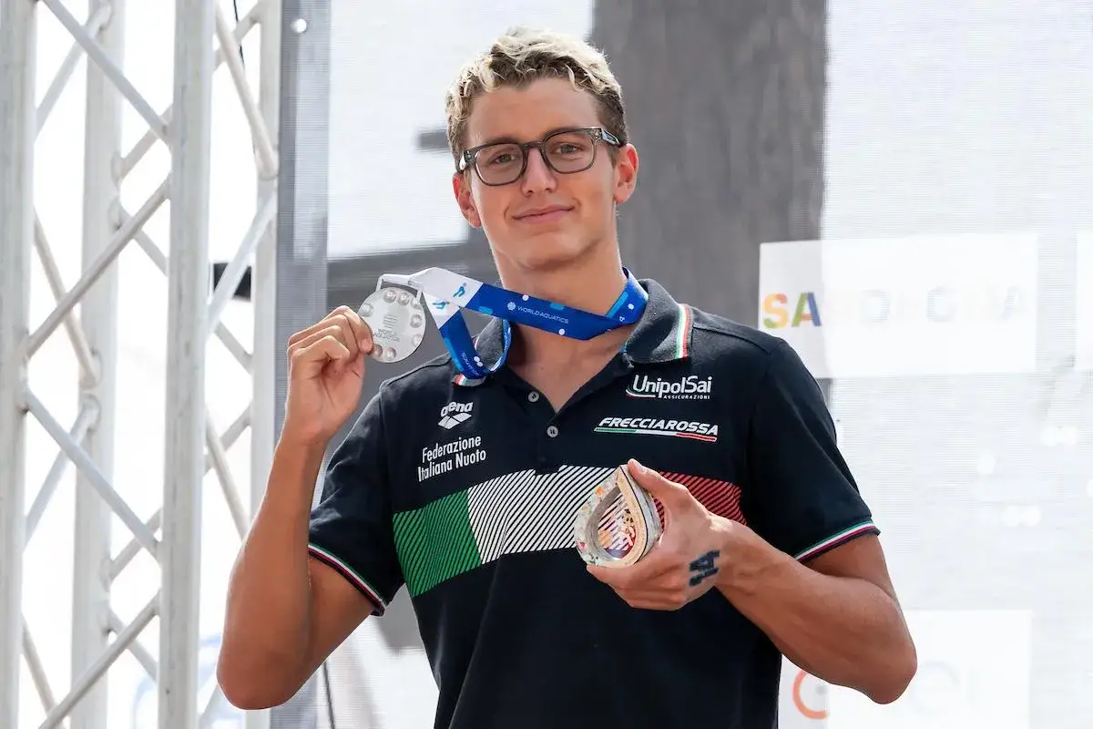 Davide Grossi, nuotatore italiano, mostra con orgoglio le sue medaglie d'argento e di bronzo, simbolo di un successo meritato.