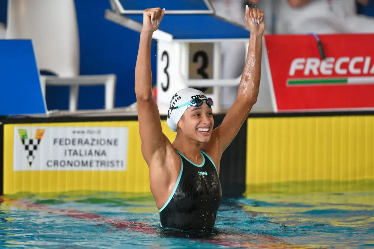 La nuotatrice Curtis festeggia la vittoria con le braccia alzate, un momento di pura gioia dopo la gara.