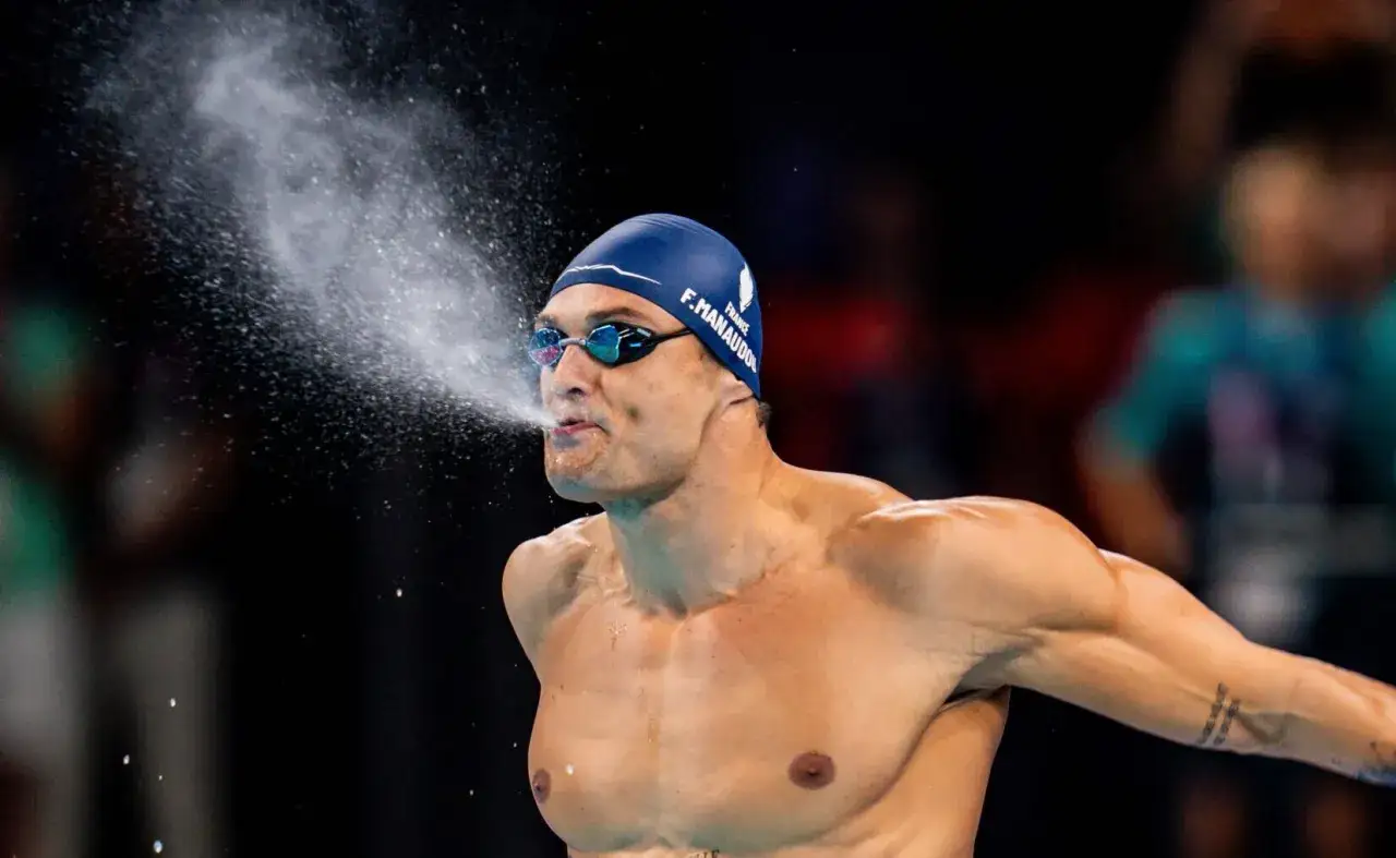 Florent Manaudou, nuotatore francese, spruzza acqua dalla bocca dopo una gara, con la cuffia blu e gli occhialini.
