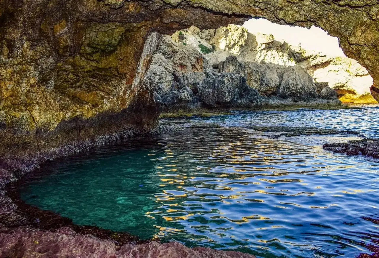 Un angolo di paradiso tra le piscine naturali Sicilia, con acque cristalline che riflettono la luce dorata tra le rocce scolpite dal mare.